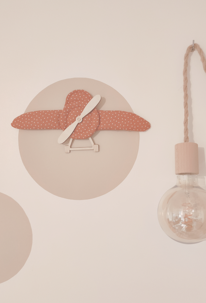 Décoration murale pour enfants en forme d'avion accrochée sur un mur avec une suspension lumineuse.